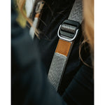 A close up of a grey camera strap with a brown leather square that has a "LP" etched into it for Lizzie Peirce.