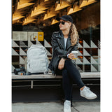 Lizzie Peirce wearing a hat and sunglasses with a camera and backpack next to her.