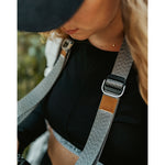 A close up of a grey camera strap attached to a camera with a brown leather square that has a "LP" etched into it for Lizzie Peirce.