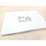 A flat, thin, white book with the words "Hokkaido in ink." above "Sopporo, Otaru & Hakodate 2019 travelogue by Mateusz Urbanowicz" in black writing. 
