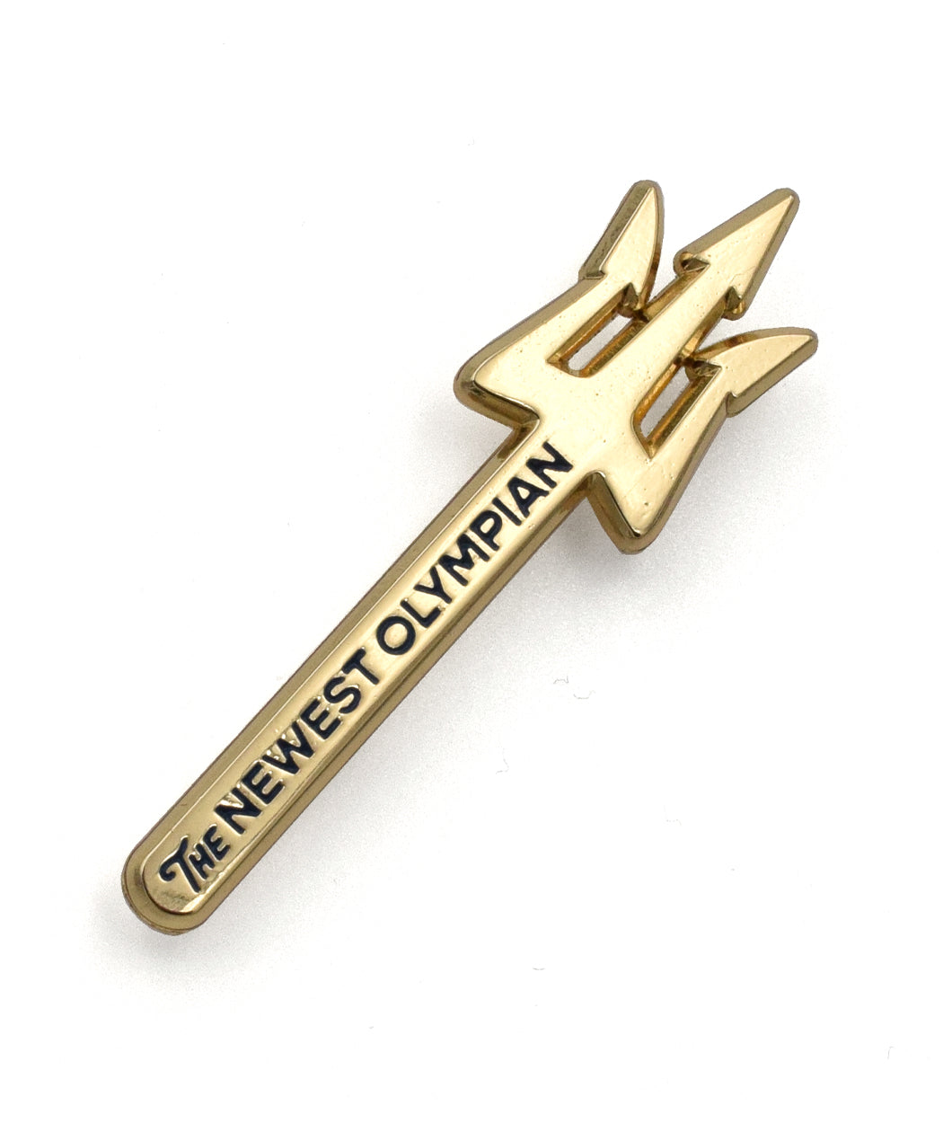 A golden pin shaped like a trident with the words "The Newest Olympian" etched in black down the staff. 