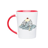 A Noble Blood white mug with red interior and handle. On the front of the mug is Marie Antoinette's bodice in a white and blue, ruffly corset with a cut off head with blood.  