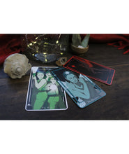 Three tarot cards fanned out in a semi circle on a dark table with a shell and jar with twinkle lights. From Spirits. 