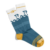 A pair of socks that are mostly blue with breaking waves at the top of the socks. The very top of the socks are white with a yellow trident and the letters "TNO". The heal and toe of the sock are yellow with white text that reads "The Newest Olympian".