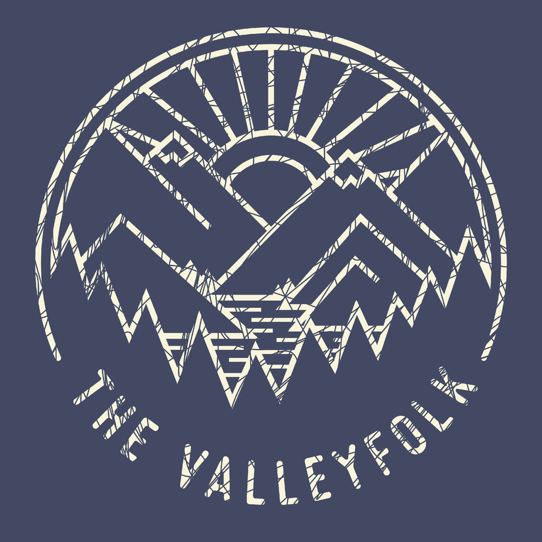 A distressed circular logo of a white outline of mountains, a lake, trees, and a sun rising. “The Valleyfolk” is arched at the bottom in white sans serif font on a navy blue background - from the Valleyfolk