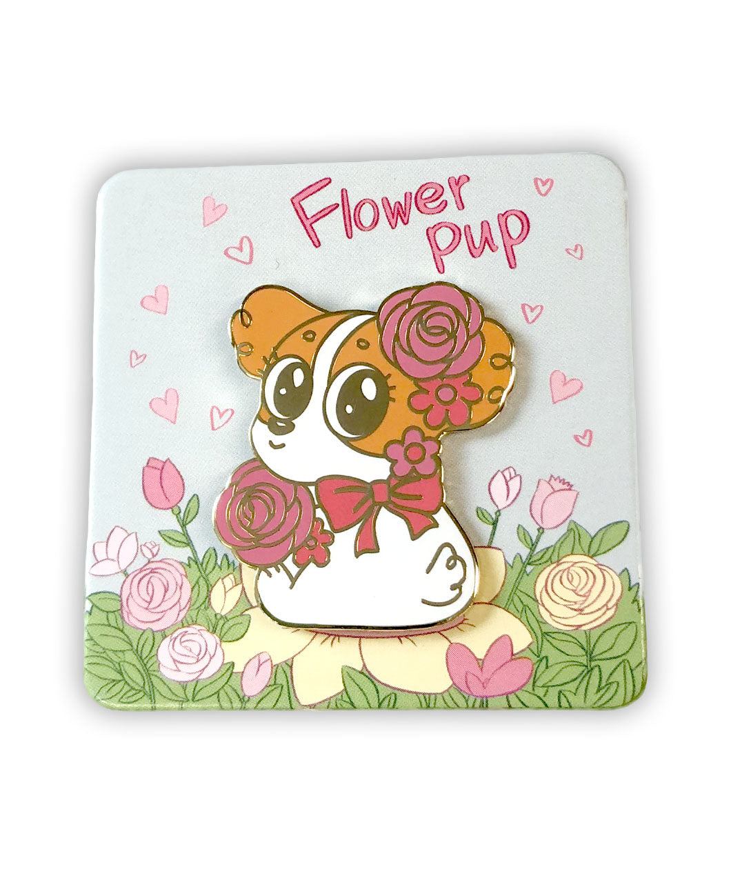 Enamel pin of an orange and white puppy sitting on the ground, looking over its should. The puppy has pink flowers around its head, and it wears a pink bow. The pin is on a square backing card that depicts a field of flowers, with the text 