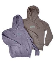 Two hoodies laying side by side, one is purple and one is grey/brown. Both are embroidered in light blue with the words "I'm thinking about books." across the chest and a small book on the right cuff.