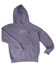 A purple hoodie with the embroidered words "I'm thinking about books." across the chest and a small book on the right cuff in light blue.