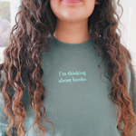 Close-up of the phrase "I'm thinking about books" written in mint on an alpine green sweatshirt worn by Ariel Bissett