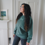 Ariel Bissett modeling an alpine green sweatshirt with mint writing on the front.