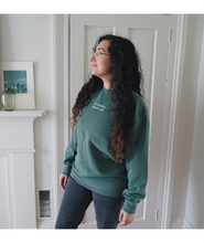 Ariel Bissett modeling an alpine green sweatshirt with mint writing on the front.
