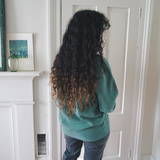 Ariel Bissett modeling the back of an alpine green sweatshirt.