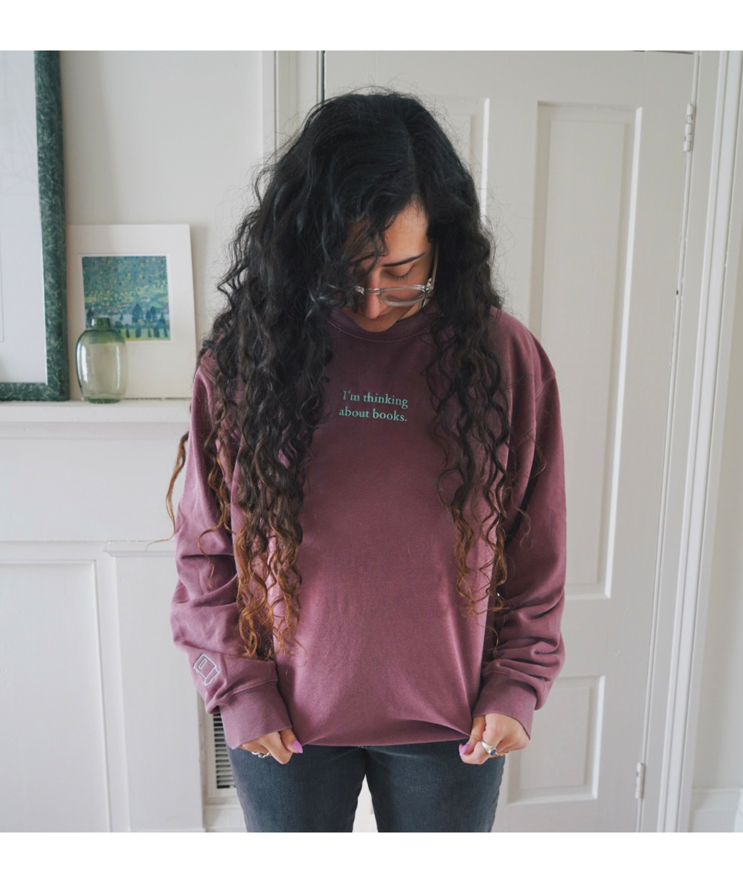 Ariel Bissett modeling a dusty rose sweatshirt with mint green writing on the front.