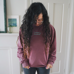 Ariel Bissett modeling a dusty rose sweatshirt with mint green writing on the front.