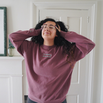Ariel Bissett modeling a dusty rose sweatshirt with mint green writing on the front.