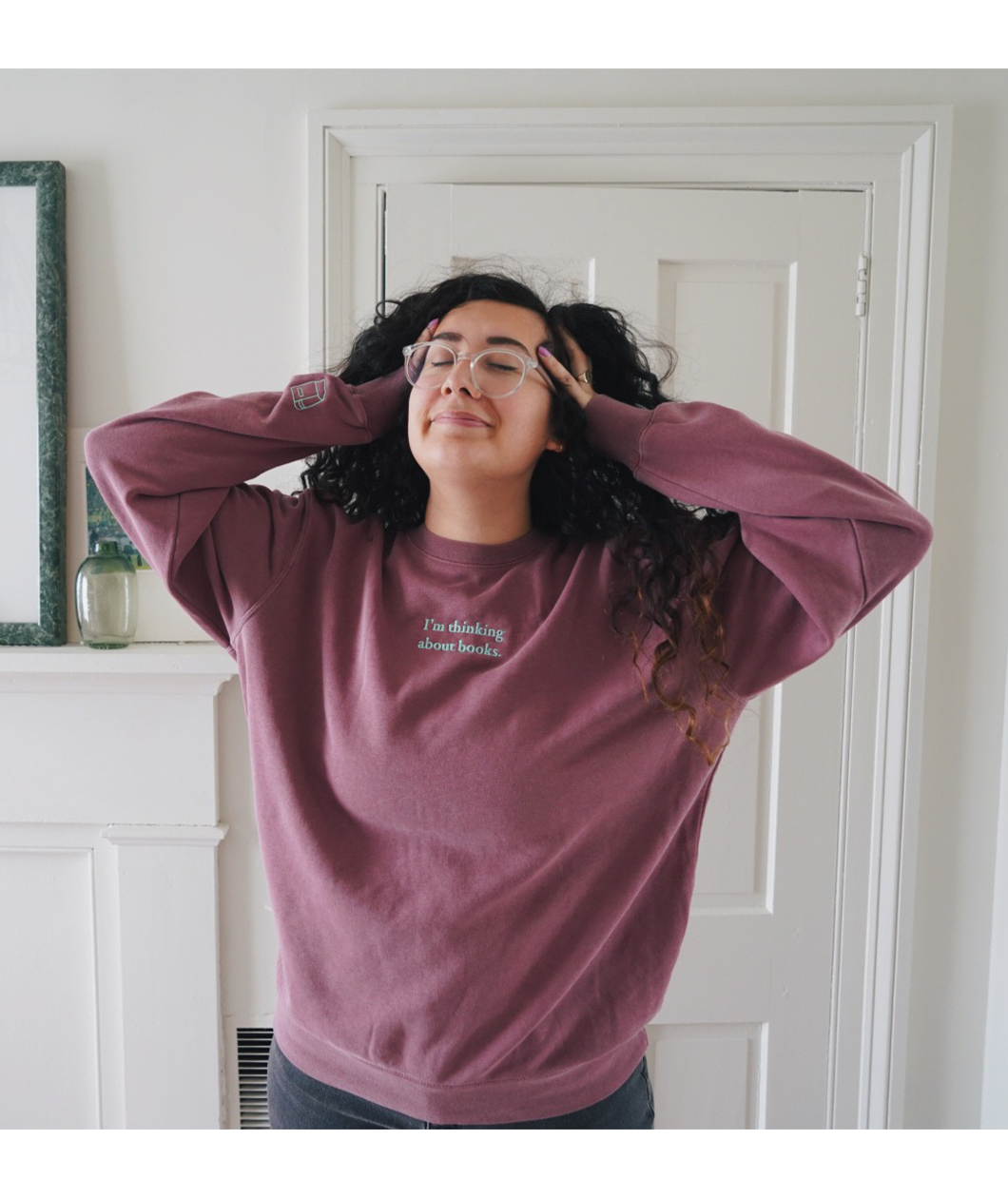 Ariel Bissett modeling a dusty rose sweatshirt with mint green writing on the front.