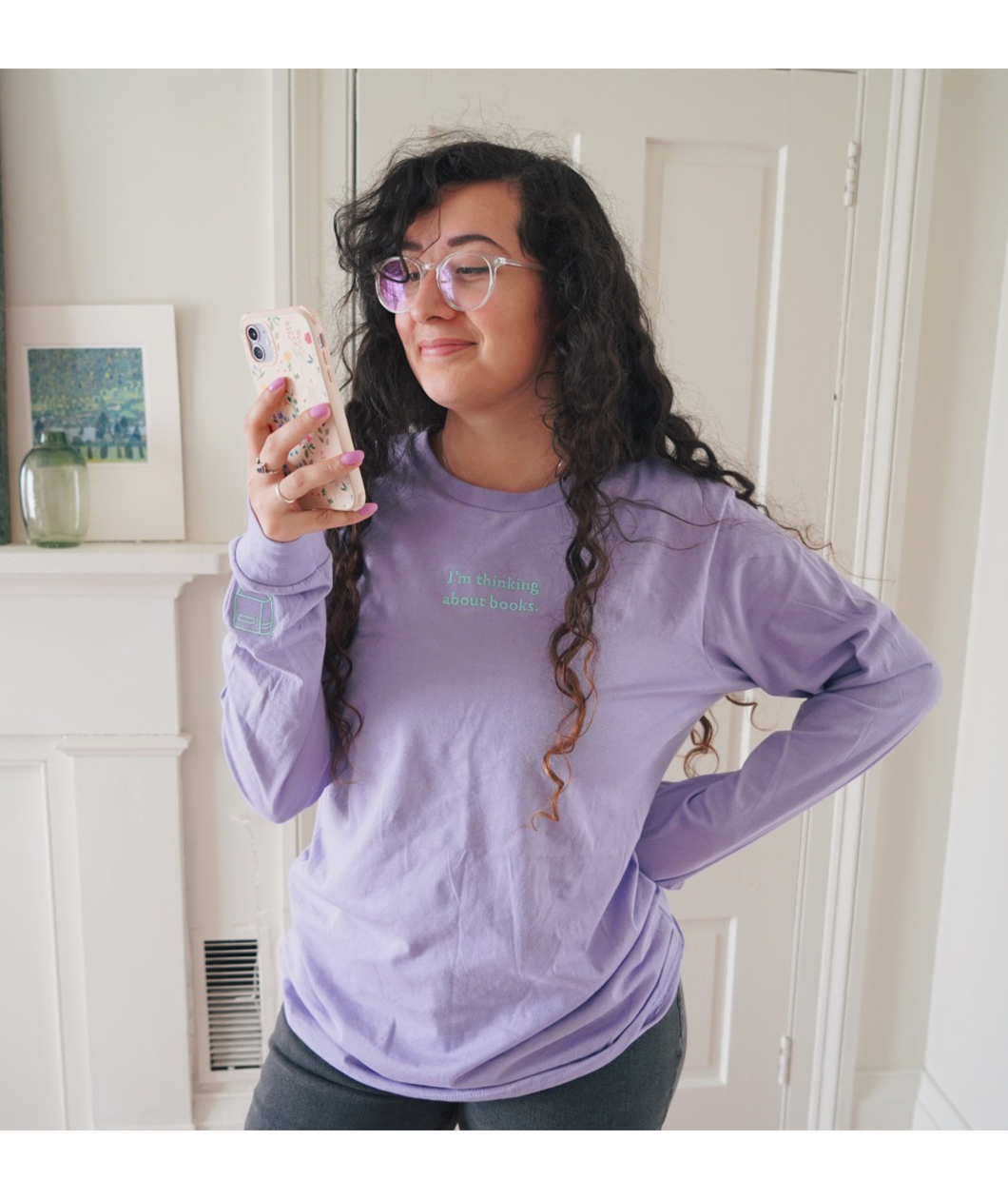 Ariel Bissett modeling a lavender long sleeve shirt with writing on the front center.