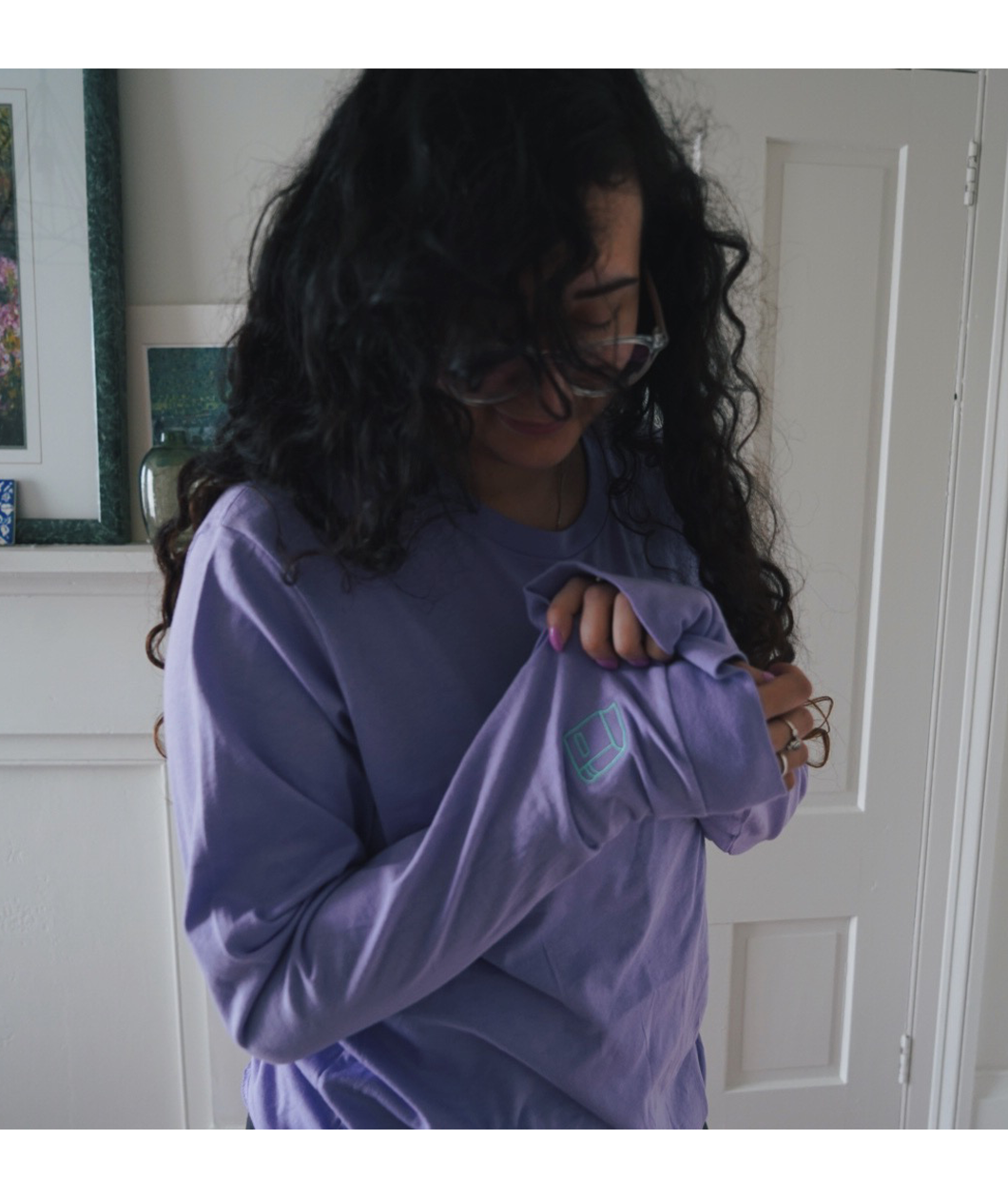 Ariel Bissett holding up the left sleeve of her lavender shirt to show the aqua outline of a book there.