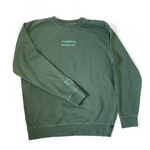 An alpine green sweatshirt with mint green writing on the front center and a small mint green outline of a book on the left sleeve - by Ariel Bissett