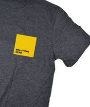 Part of a grey t-shirt that has a yellow square with the words "Beautiful Nerd" inside it - by 99% Invisible