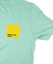 Part of a mint t-shirt that has a yellow square with the words "Beautiful Nerd" inside it - by 99% Invisible