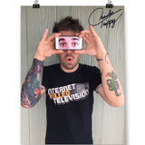 A signed photo of Charles Trippy holding an iphone showing a photo of eyes over his eyes