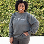 Melissa Monts modeling a gray crewneck sweatshirt with “don’t blame me” across chest in white cursive font - from Don’t Blame Me