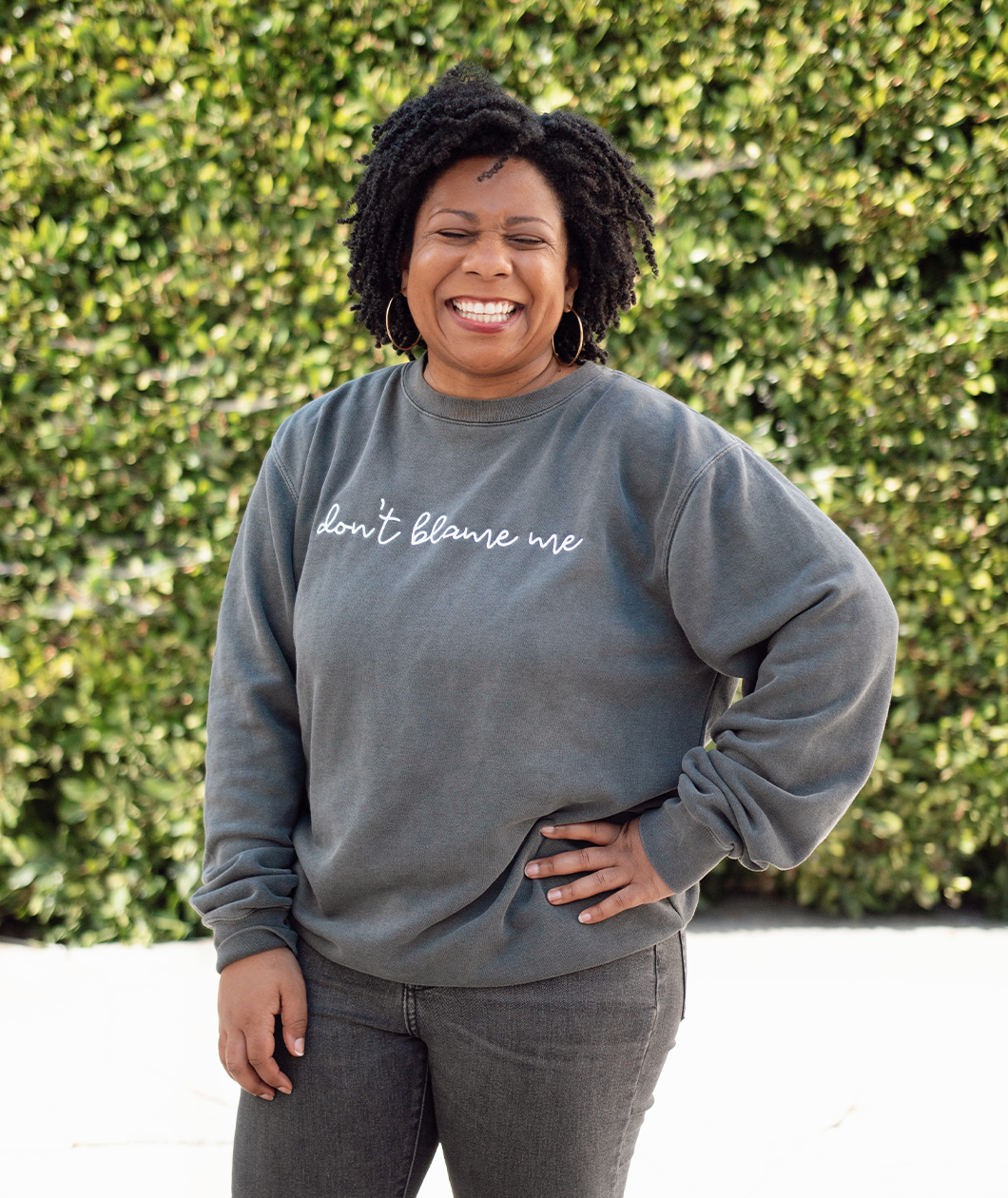 Melissa Monts modeling a gray crewneck sweatshirt with “don’t blame me” across chest in white cursive font - from Don’t Blame Me