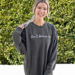 Meghan Rienks modeling a gray crewneck sweatshirt with “don’t blame me” across chest in white cursive font - from Don’t Blame Me