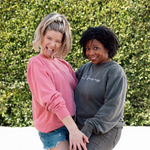 Meghan Rienks modeling a pink crewneck sweatshirt with “don’t blame me” across the chest in pink serif font and Melisa Monts modeling a gray crewneck sweatshirt with “don’t blame me” across chest in white cursive font - from Don’t Blame Me