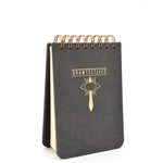 A small black notepad with gold spirals and the word "drawtectives" with a drawing of a sword and eye in gold in the center - by Drawfee