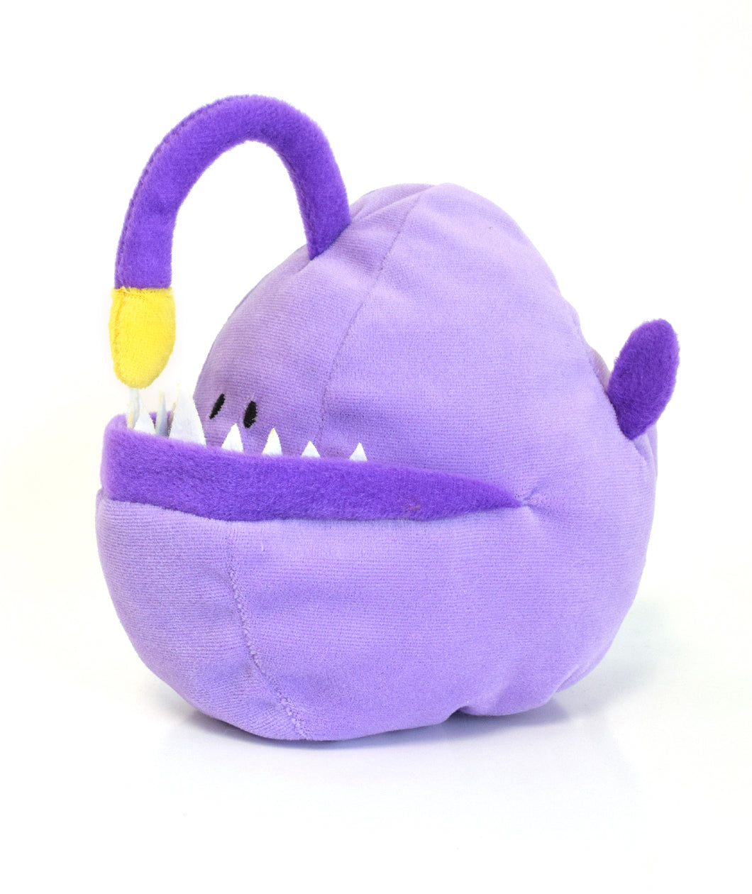 A purple anglerfish plushie with dark purple fin, lower lip, and angler. Yellow bulb is at the end of angler. Plushie has an underbite and sharp white teeth and two small eyes - from DFTBA