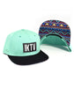 Aqua trucker hat with a black square on the front with white letters "IKTV." The bill is black on the top and has a blue, red, and yellow pattern on the bottom. By Charles Trippy