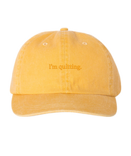 Yellow hat with “I’m quitting” in orange centered on front of hat - from Iz Harris