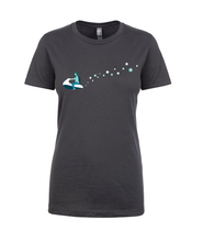 A dark gray shirt with a monochrome blue cartoon drawing of a man with a beard and long hair riding a white and blue jet ski. Following the jet ski are a series of different sized circles in different tones of blue - from JoCo Cruise