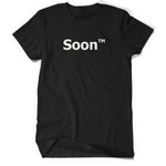 A black shirt with “Soon” in white sans serif font across the front. Following the word is “TM” at the top right of the word in white sans serif font - from JoCo Cruise