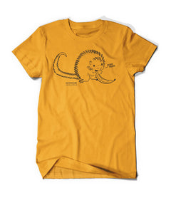Yellow shirt with cartoon, black line drawing of porcupine eating a banana all with yellow fill. "Kemosabe” is written in black sans serif font in bottom left of porcupine. "Coendou prehensilis” is below in cursive black font.” On right, black line leads from mouth with “nom nom” in black sans serif font - from Animal wonders