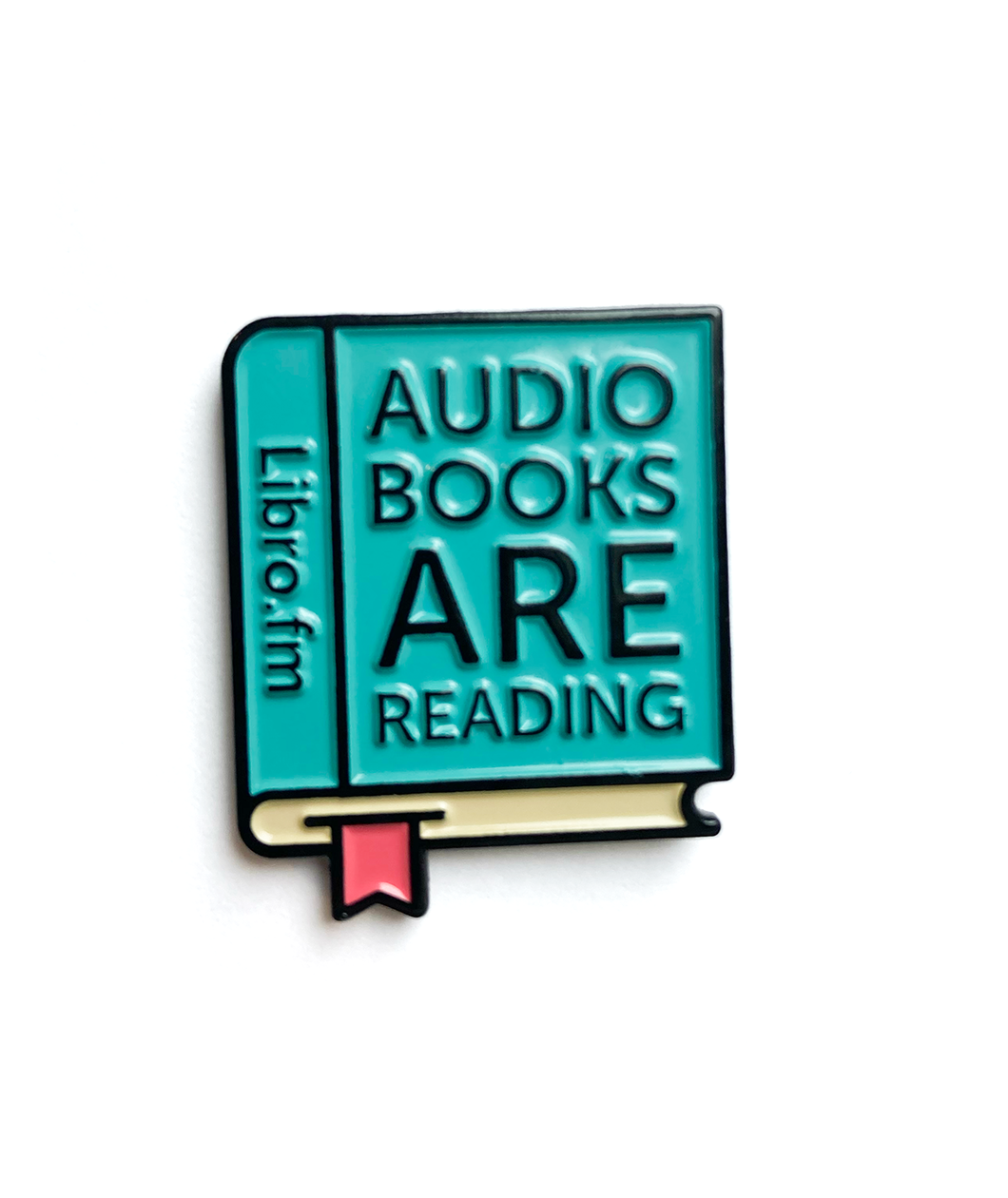 A cartoon drawn teal book with a red bookmark coming out of the bottom. “Libro.fm” is in black sans serif font on the spine. “Audiobooks are reading” is on the cover in black sans serif font - from Libro.fm