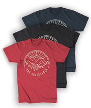 Red, black and navy shirts with a distressed circular logo of a white outline of mountains, a lake, trees, and a sun rising. “The Valleyfolk” is arched at the bottom in white sans serif font - from the Valleyfolk
