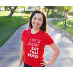 A bright red t-shirt with the words "Life Is Short Eat Thai Food" written down the right side worn by Pailin from Hot Thai Kitchen. 