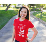 A bright red t-shirt with the words "Life Is Short Eat Thai Food" written down the right side worn by Pailin from Hot Thai Kitchen. 