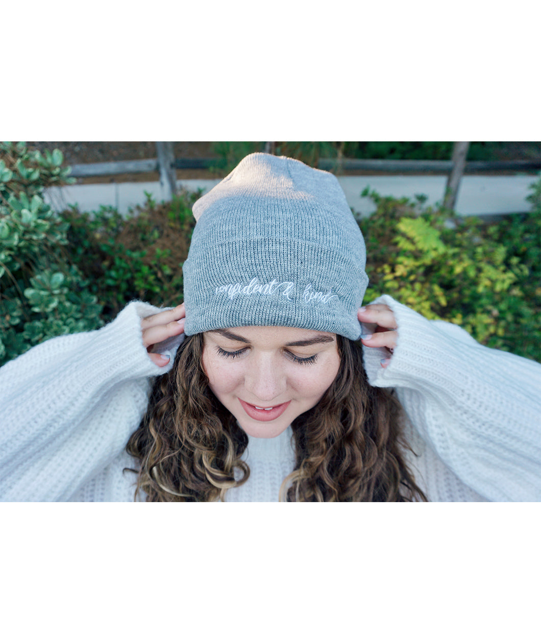 A woman modeling a gray beanie with “confident & kind” in white cursive font across the cuff - from Sierra Schultzzie