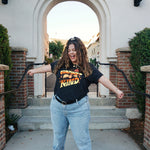 A girl modeling a blue shirt with “Confident & Kind” in half yellow and half orange organic fond. The words are surrounded by various flowers and stars - from Sierra Schultzzie