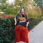 A girl modeling a blue shirt with “Confident & Kind” in half yellow and half orange organic fond. The words are surrounded by various flowers and stars - from Sierra Schultzzie
