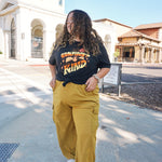 A girl modeling a blue shirt with “Confident & Kind” in half yellow and half orange organic fond. The words are surrounded by various flowers and stars - from Sierra Schultzzie