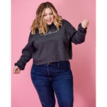 A woman modeling a dark gray crop top hoodie with “unfiltered” in white cursive font across the chest - from Sierra Schultzzie