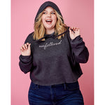 A woman modeling a dark gray crop top hoodie with “unfiltered” in white cursive font across the chest - from Sierra Schultzzie