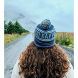 A person with their back to the camera with flowing brown hair wearing a blue knit beanie that reads "Chi Kappa". From Sierra Schultzzie.