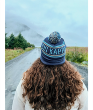 A person with their back to the camera with flowing brown hair wearing a blue knit beanie that reads "Chi Kappa". From Sierra Schultzzie.