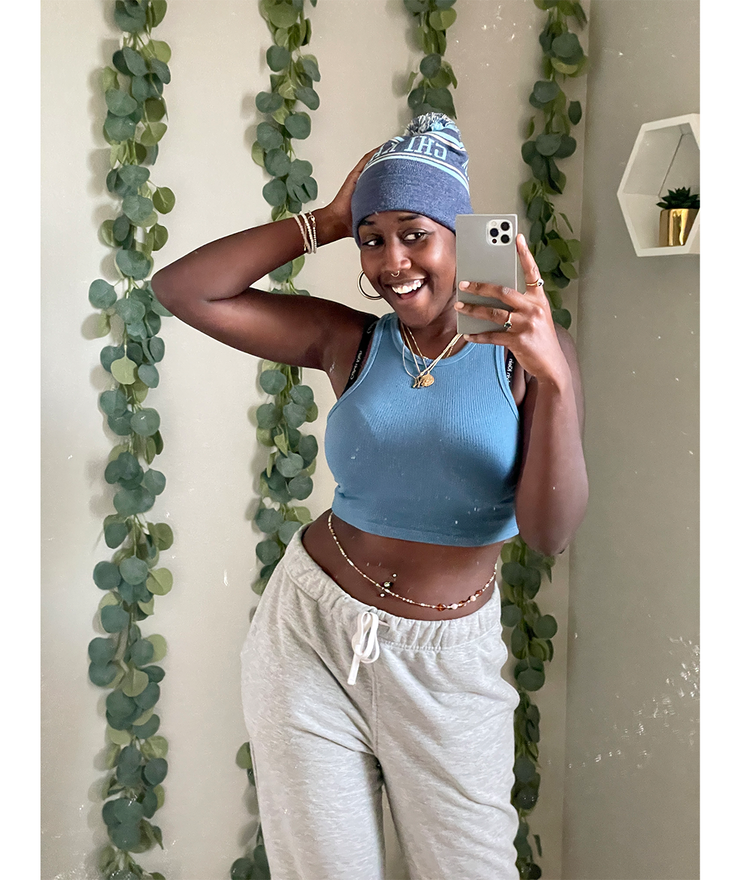 A person taking a mirror selfie, smiling, wearing a blue knit beanie that reads "Chi Kappa". From Sierra Schultzzie.